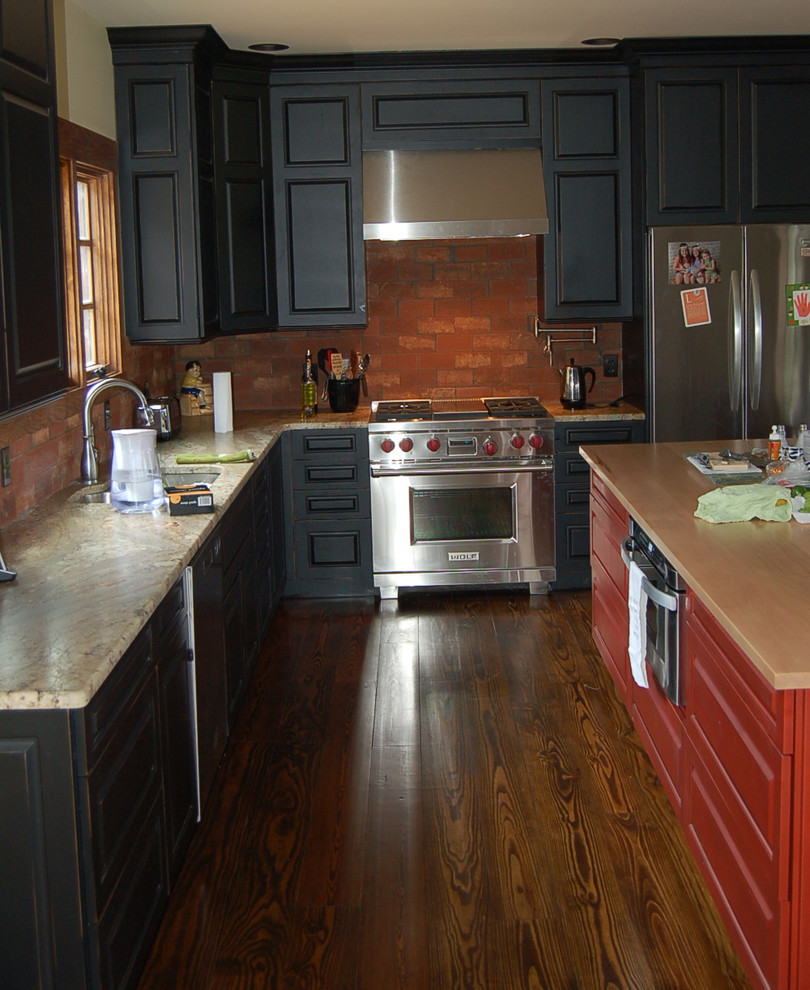 Immagine di una cucina stile rurale con ante nere, elettrodomestici in acciaio inossidabile, lavello sottopiano, ante con bugna sagomata, top in granito, paraspruzzi rosso e parquet scuro