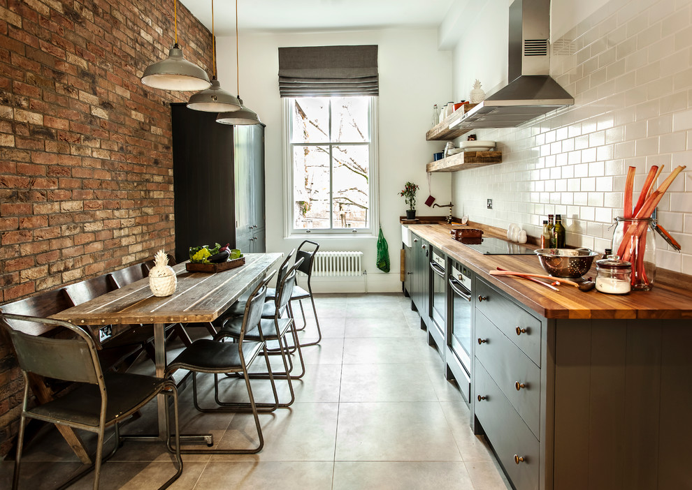 Mid-sized urban single-wall enclosed kitchen photo in London with wood countertops, white backsplash, subway tile backsplash and no island
