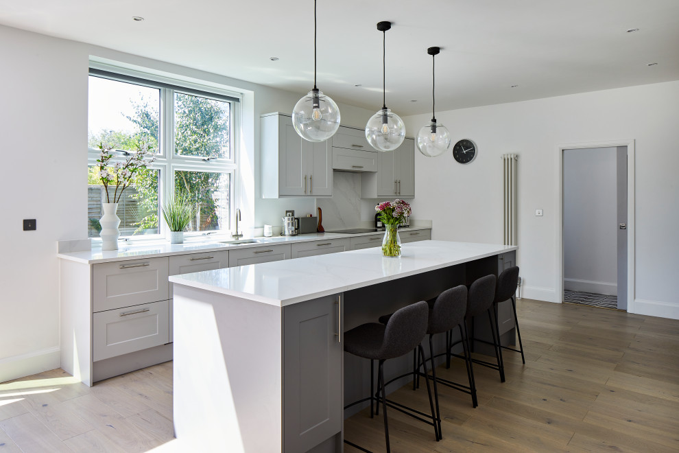 Foto di una cucina classica con lavello sottopiano, ante in stile shaker, ante grigie, pavimento in legno massello medio, pavimento marrone e top bianco