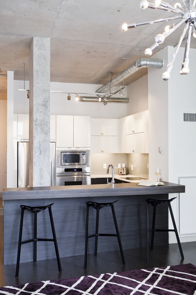 Inspiration for an industrial kitchen remodel in Toronto with flat-panel cabinets and stainless steel appliances