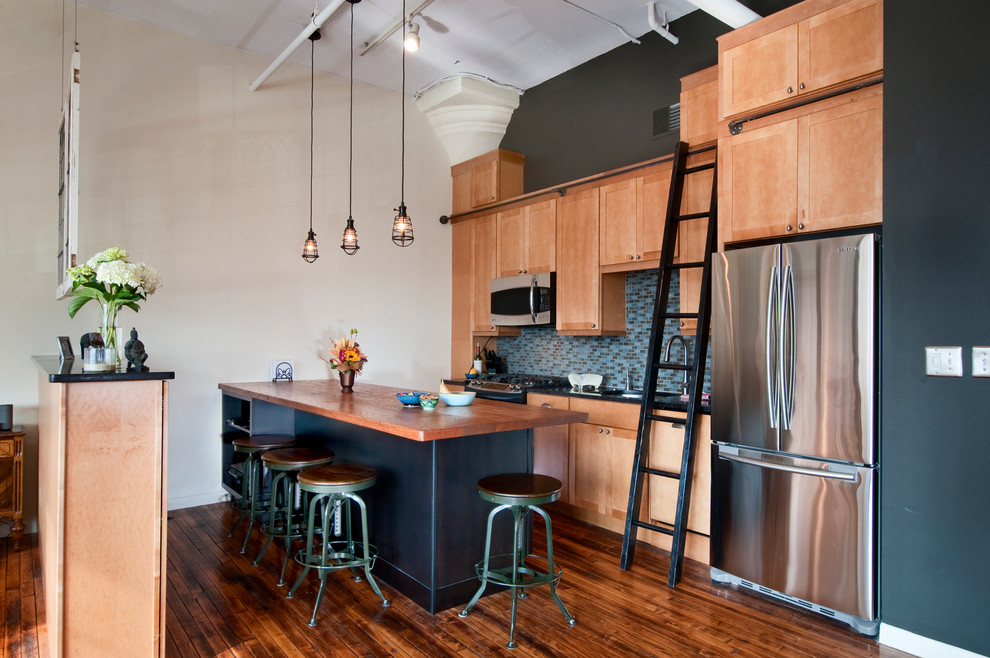 This is an example of an urban single-wall kitchen in Philadelphia with stainless steel appliances, wood worktops, shaker cabinets, medium wood cabinets and blue splashback.