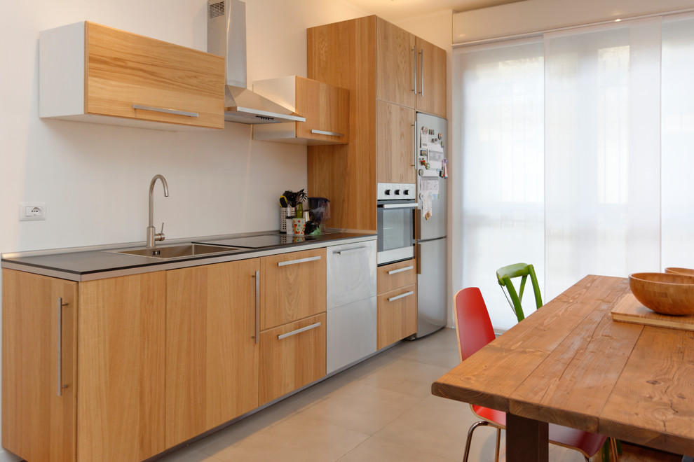 Example of a mid-sized trendy single-wall concrete floor eat-in kitchen design in Milan with a single-bowl sink, flat-panel cabinets, medium tone wood cabinets, laminate countertops, white backsplash and stainless steel appliances