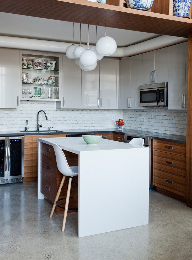 This is an example of a medium sized contemporary l-shaped kitchen in Toronto with a submerged sink, flat-panel cabinets, white cabinets, white splashback, stainless steel appliances, concrete flooring and an island.