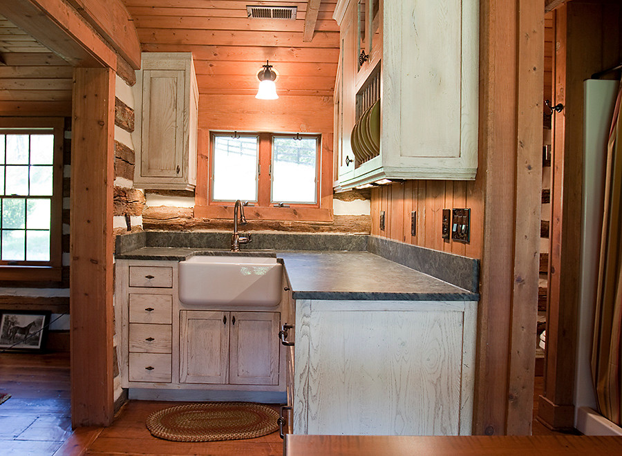 Enclosed kitchen - small cottage l-shaped medium tone wood floor enclosed kitchen idea in DC Metro with a farmhouse sink, flat-panel cabinets, distressed cabinets, granite countertops, paneled appliances and no island