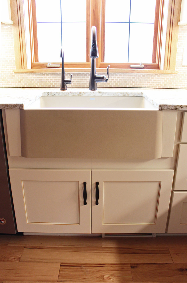 Example of a mid-sized mountain style galley eat-in kitchen design in Cleveland with a farmhouse sink, recessed-panel cabinets, white cabinets, granite countertops, beige backsplash, mosaic tile backsplash, stainless steel appliances, an island and beige countertops