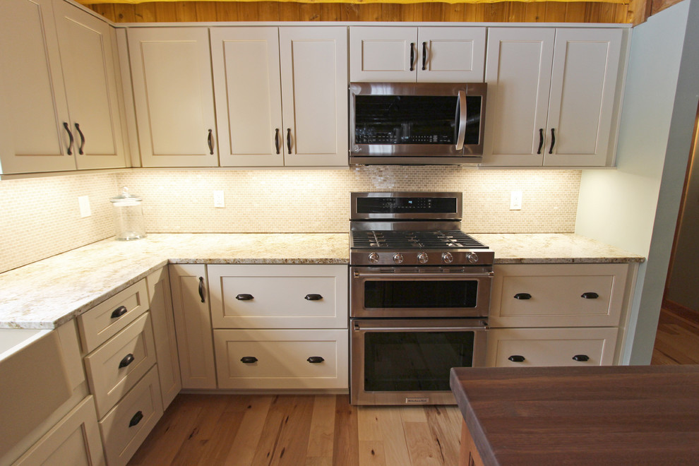 This is an example of a medium sized rustic galley kitchen/diner in Cleveland with a belfast sink, recessed-panel cabinets, white cabinets, granite worktops, beige splashback, mosaic tiled splashback, stainless steel appliances, an island and beige worktops.