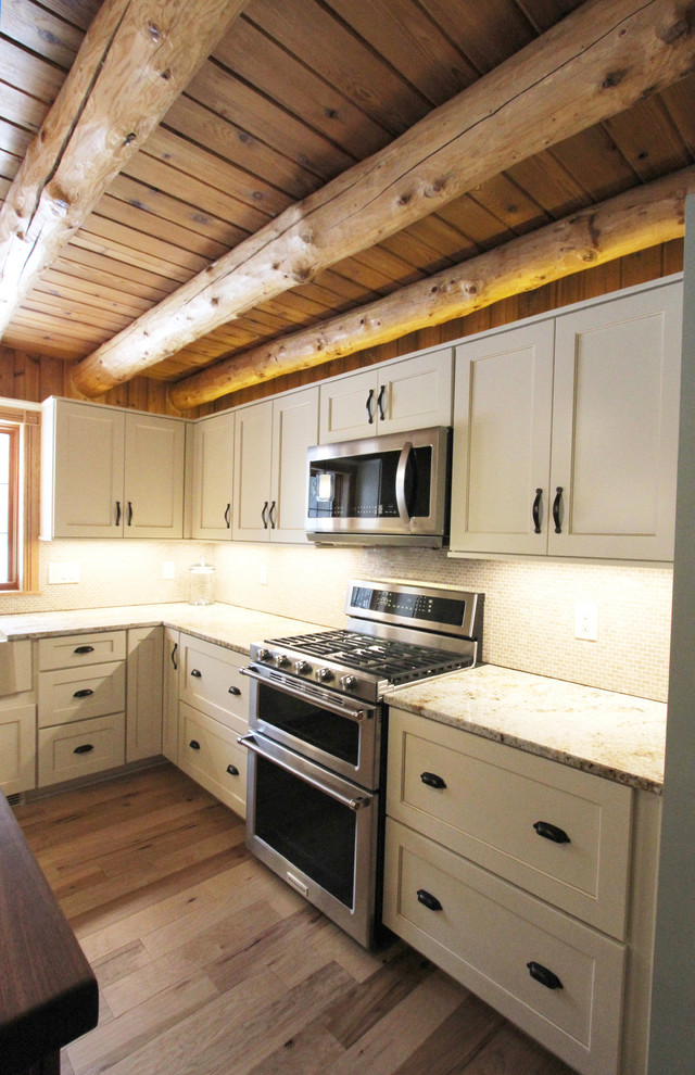 Rustik inredning av ett mellanstort beige beige kök, med en rustik diskho, luckor med infälld panel, vita skåp, granitbänkskiva, beige stänkskydd, stänkskydd i mosaik, rostfria vitvaror och en köksö