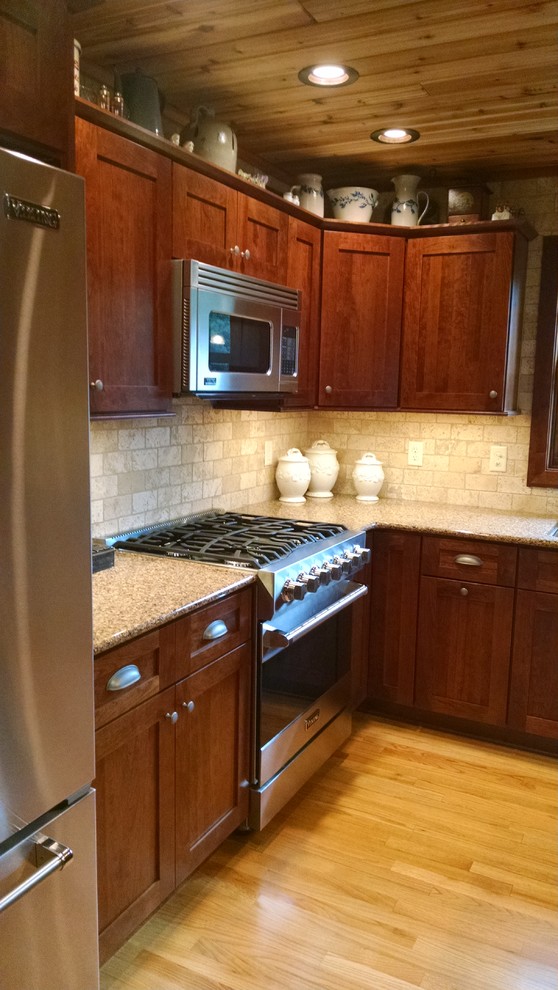 Bild på ett mellanstort amerikanskt kök, med en undermonterad diskho, skåp i shakerstil, bänkskiva i kvarts, beige stänkskydd, stänkskydd i stenkakel, rostfria vitvaror, ljust trägolv och en köksö