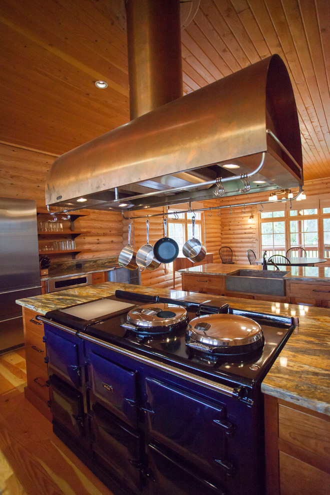 This is an example of an expansive rustic l-shaped kitchen/diner in Seattle with a belfast sink, shaker cabinets, medium wood cabinets, granite worktops, brown splashback, stone slab splashback, stainless steel appliances, medium hardwood flooring, multiple islands, brown floors and multicoloured worktops.