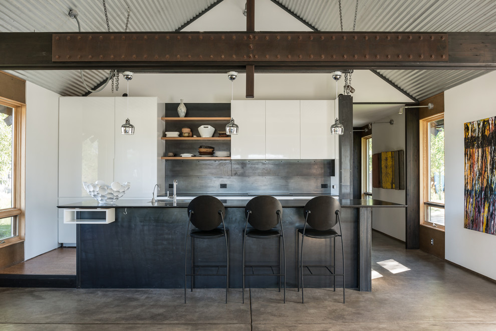 Пример оригинального дизайна: параллельная кухня в стиле лофт с плоскими фасадами, белыми фасадами, фартуком цвета металлик, бетонным полом и островом
