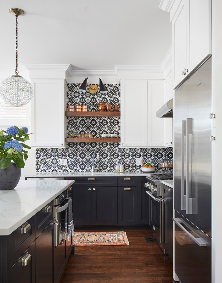 Bild på ett stort vintage vit vitt kök, med en undermonterad diskho, skåp i shakerstil, bänkskiva i kvartsit, svart stänkskydd, stänkskydd i cementkakel, rostfria vitvaror, mellanmörkt trägolv, en köksö och brunt golv
