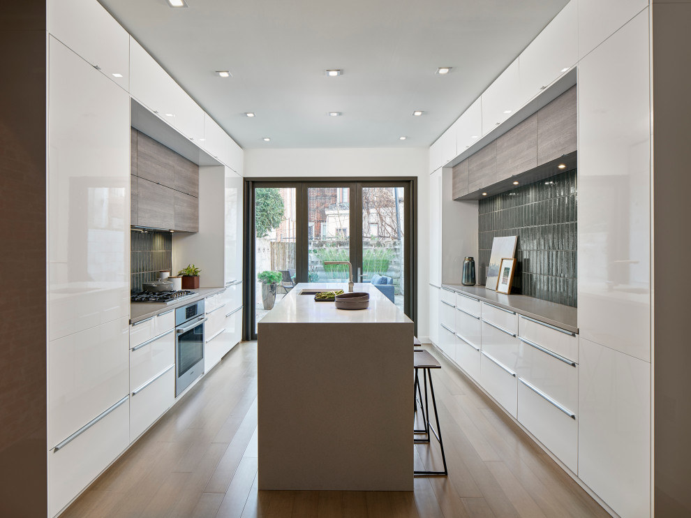 Cette photo montre une cuisine parallèle moderne avec un placard à porte plane, un plan de travail en quartz modifié, parquet en bambou et îlot.