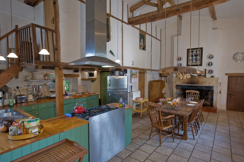 Exemple d'une cuisine américaine nature avec des portes de placards vertess, un plan de travail en bois et un électroménager en acier inoxydable.