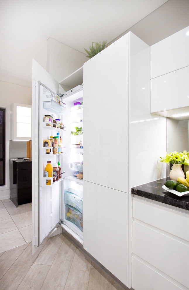 Immagine di una grande cucina minimalista con lavello sottopiano, top in granito, paraspruzzi a specchio, elettrodomestici neri, pavimento in gres porcellanato, pavimento bianco e top nero