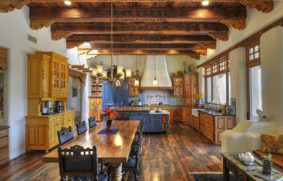 Пример оригинального дизайна: угловая кухня в стиле фьюжн с с полувстраиваемой мойкой (с передним бортиком), фасадами с выступающей филенкой, фасадами цвета дерева среднего тона, синим фартуком, темным паркетным полом и островом