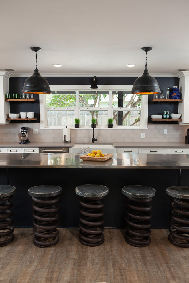 Bild på ett stort industriellt grå grått kök med öppen planlösning, med en rustik diskho, luckor med infälld panel, vita skåp, beige stänkskydd, stänkskydd i porslinskakel, rostfria vitvaror, en köksö, brunt golv, bänkskiva i rostfritt stål och vinylgolv