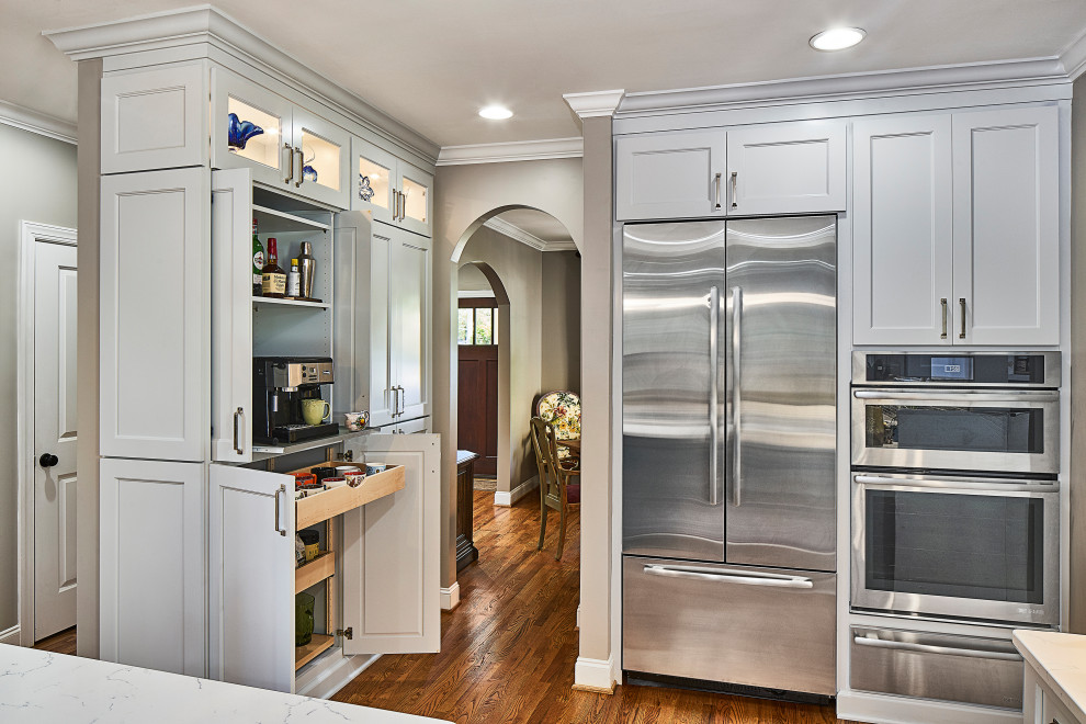 Foto på ett mellanstort vintage vit kök, med en undermonterad diskho, luckor med infälld panel, blå skåp, bänkskiva i kvarts, blått stänkskydd, stänkskydd i glaskakel, rostfria vitvaror, mellanmörkt trägolv, en köksö och brunt golv
