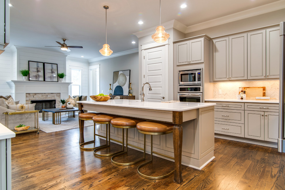 Exempel på ett klassiskt vit vitt kök, med en rustik diskho, luckor med infälld panel, grå skåp, vitt stänkskydd, rostfria vitvaror, mörkt trägolv, en köksö och brunt golv