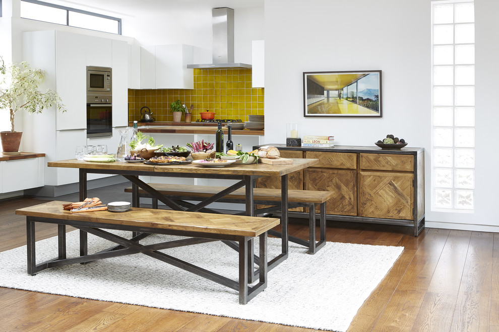 Inspiration for a small urban l-shaped kitchen/diner in London with flat-panel cabinets, white cabinets, wood worktops, yellow splashback, ceramic splashback, stainless steel appliances, dark hardwood flooring and a breakfast bar.