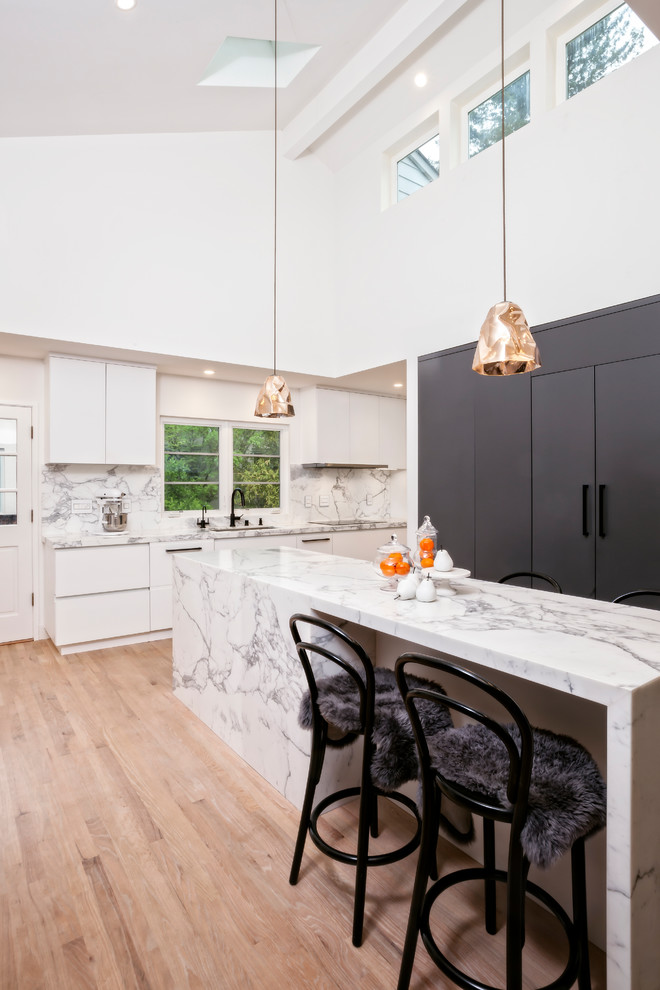 Exempel på ett mellanstort modernt kök, med en undermonterad diskho, släta luckor, grå skåp, marmorbänkskiva, vitt stänkskydd, stänkskydd i marmor, rostfria vitvaror, ljust trägolv, en köksö och brunt golv