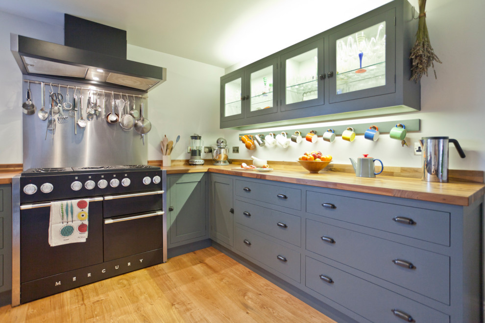 Large traditional l-shaped kitchen/diner in Gloucestershire with a submerged sink, shaker cabinets, grey cabinets, wood worktops, metallic splashback, stainless steel appliances, medium hardwood flooring, no island, brown floors and brown worktops.