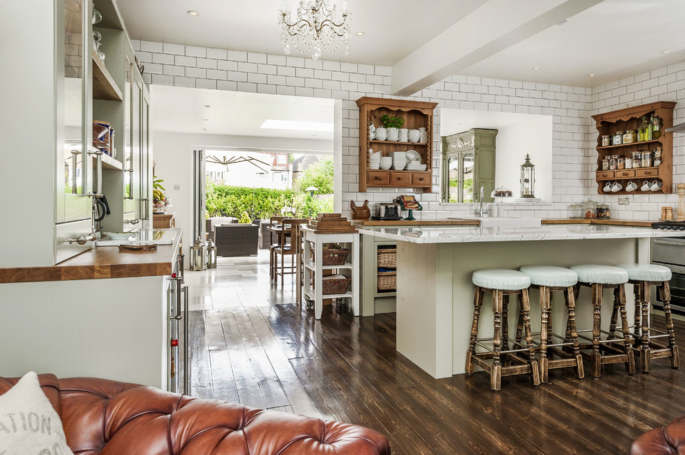 Klassische Küche in U-Form mit Küchenrückwand in Weiß, Rückwand aus Metrofliesen, dunklem Holzboden und Kücheninsel in London