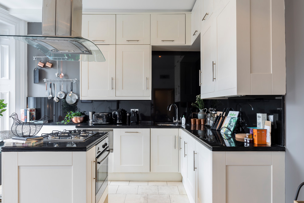 Bild på ett minimalistiskt l-kök, med en undermonterad diskho, skåp i shakerstil, vita skåp, svart stänkskydd, en köksö och vitt golv