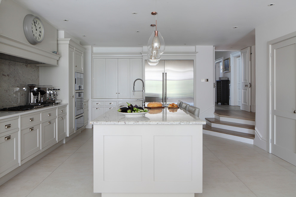 Photo of a traditional l-shaped kitchen in London with a submerged sink, shaker cabinets, white cabinets, grey splashback, stainless steel appliances, an island, beige floors and white worktops.
