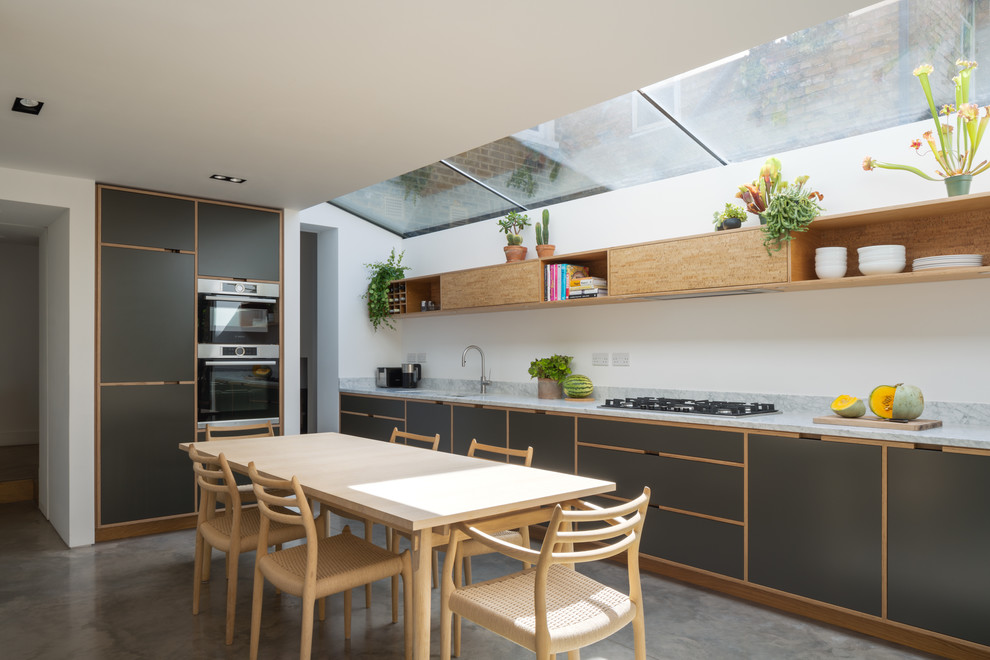 Photo of a medium sized contemporary grey and cream kitchen/diner in London with a submerged sink, flat-panel cabinets, grey cabinets, grey splashback, stainless steel appliances, concrete flooring, grey floors and grey worktops.