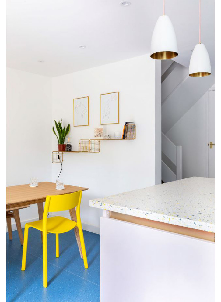 Пример оригинального дизайна: маленькая угловая кухня в современном стиле с обеденным столом, одинарной мойкой, плоскими фасадами, столешницей терраццо, разноцветным фартуком, техникой под мебельный фасад, полом из ламината, островом, синим полом и разноцветной столешницей для на участке и в саду