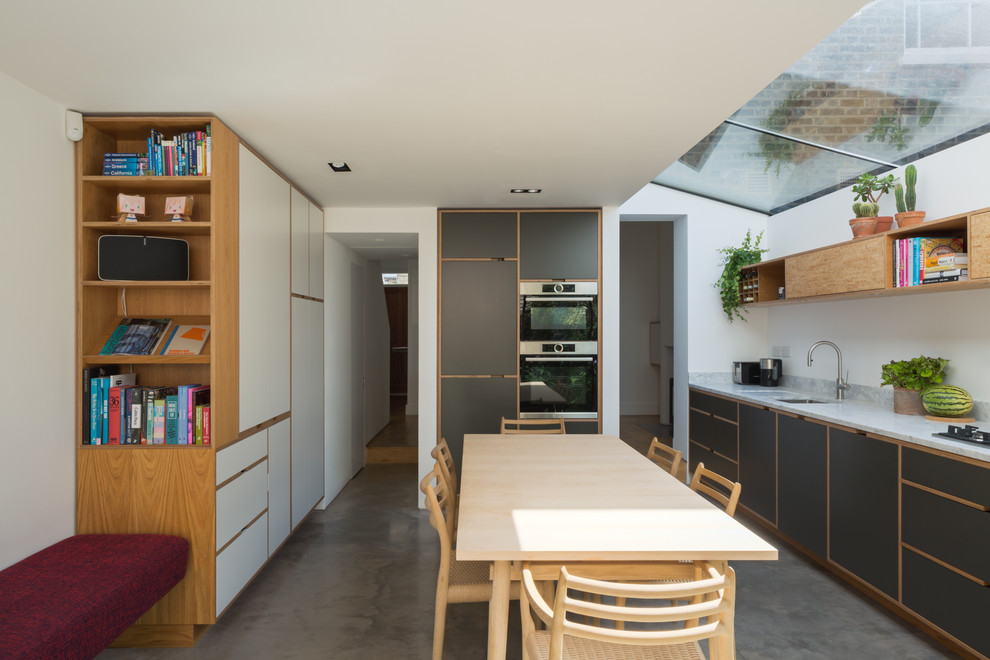 Idéer för funkis kök, med en undermonterad diskho, släta luckor, marmorbänkskiva, integrerade vitvaror, betonggolv och grått golv