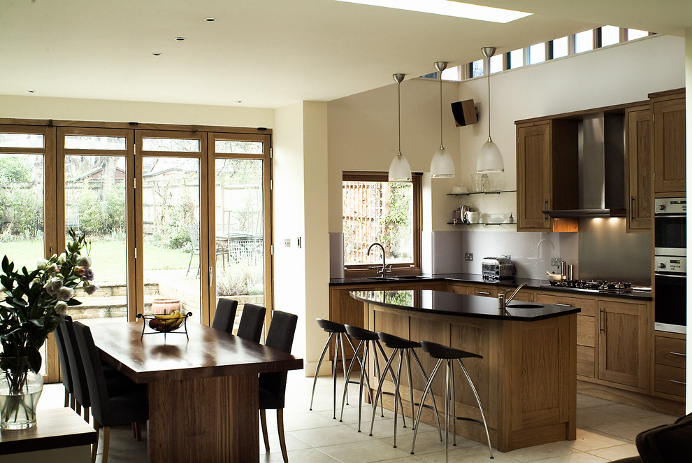 This is an example of a contemporary l-shaped open plan kitchen in London with shaker cabinets, medium wood cabinets, grey splashback, stainless steel appliances and an island.