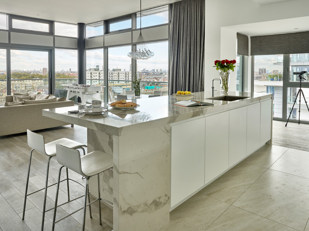 Bild på ett mellanstort funkis linjärt kök med öppen planlösning, med en dubbel diskho, släta luckor, vita skåp, marmorbänkskiva, vitt stänkskydd, stänkskydd i sten, rostfria vitvaror och en köksö