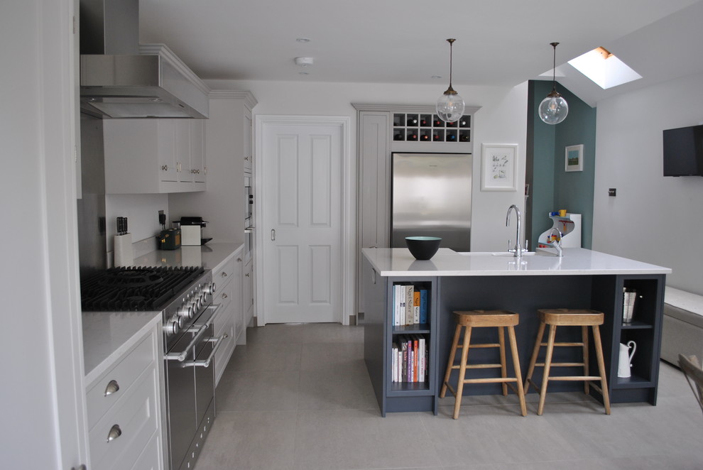 Foto di una cucina minimal di medie dimensioni con lavello stile country, ante in stile shaker, paraspruzzi a effetto metallico, elettrodomestici in acciaio inossidabile, pavimento grigio e top bianco
