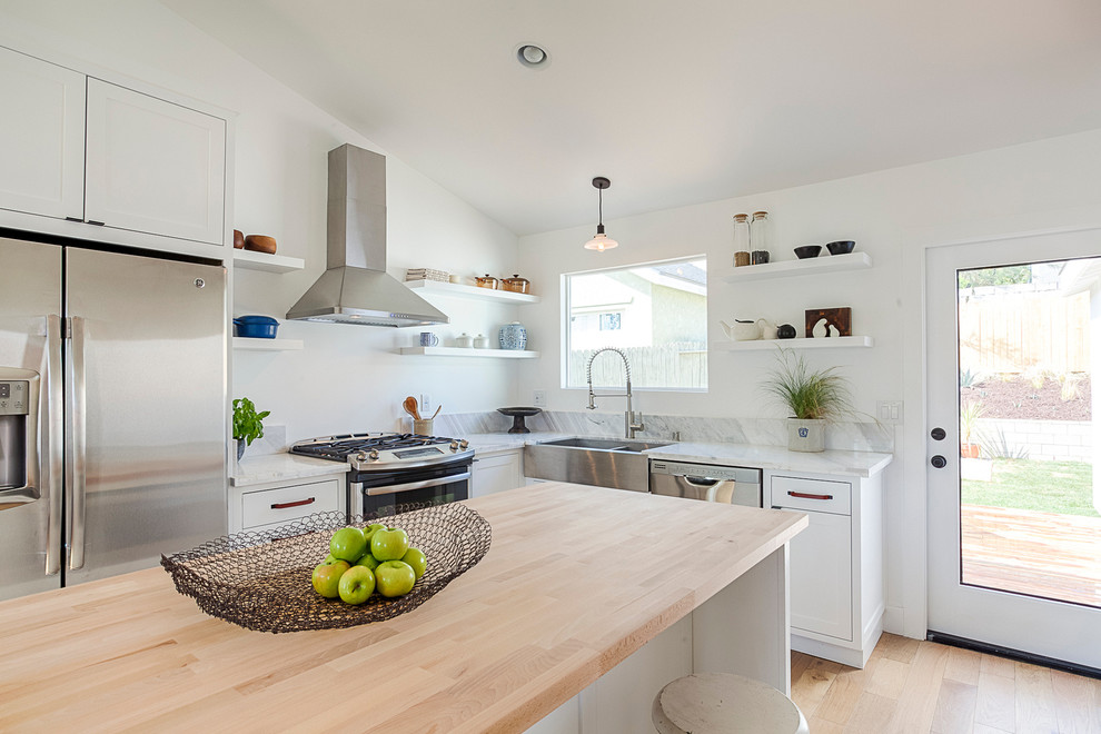 Modern inredning av ett litet kök, med en rustik diskho, vita skåp, marmorbänkskiva, rostfria vitvaror, ljust trägolv och en köksö