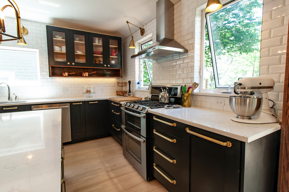 Example of a mid-sized transitional l-shaped light wood floor and white floor eat-in kitchen design in Other with an undermount sink, shaker cabinets, black cabinets, quartz countertops, white backsplash, ceramic backsplash, stainless steel appliances, an island and white countertops