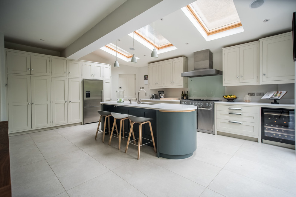 Photo of an expansive contemporary kitchen/diner in London with a double-bowl sink, engineered stone countertops, stainless steel appliances, ceramic flooring, an island, shaker cabinets and glass sheet splashback.