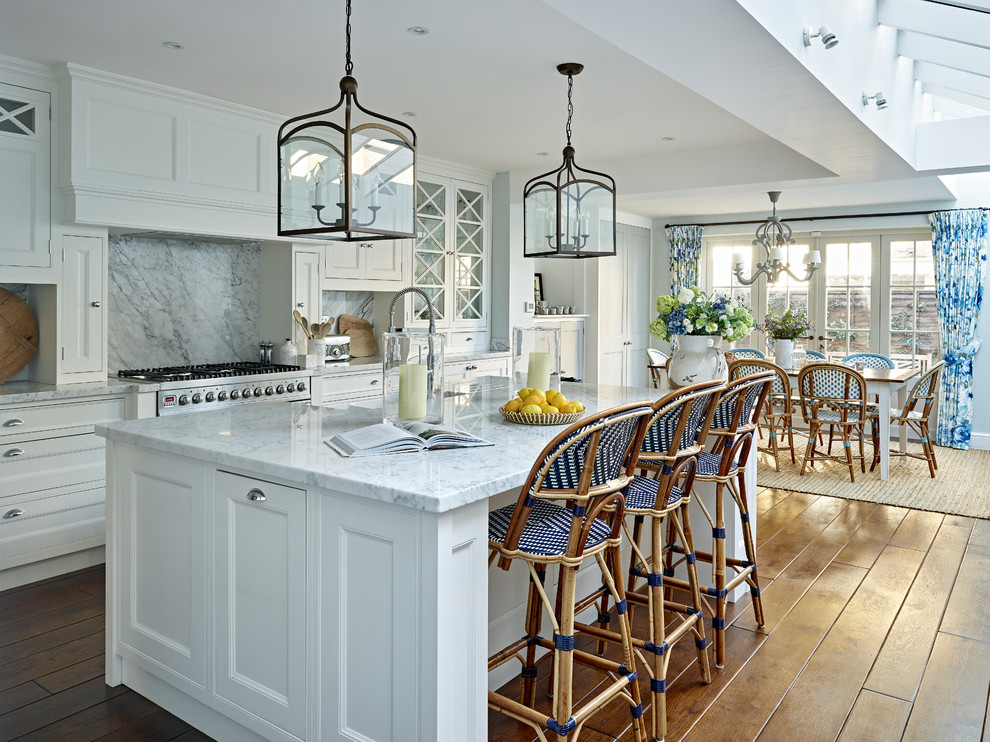 Medium sized classic single-wall kitchen in London with shaker cabinets, white cabinets, marble worktops, white splashback, marble splashback, stainless steel appliances, medium hardwood flooring, an island, brown floors and white worktops.