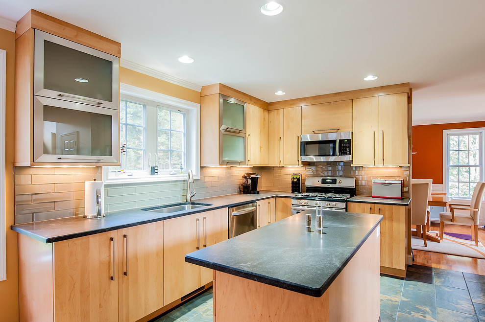 Exempel på ett modernt kök, med en undermonterad diskho, släta luckor, skåp i ljust trä, granitbänkskiva, grått stänkskydd, stänkskydd i glaskakel, rostfria vitvaror, klinkergolv i porslin och en köksö
