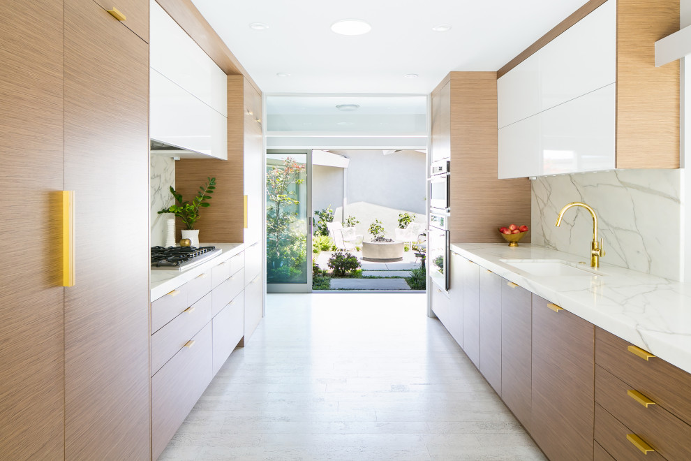 Kitchen - mid-sized contemporary galley cork floor and white floor kitchen idea in Orange County with an undermount sink, flat-panel cabinets, medium tone wood cabinets, marble countertops, white backsplash, marble backsplash, paneled appliances, no island and white countertops