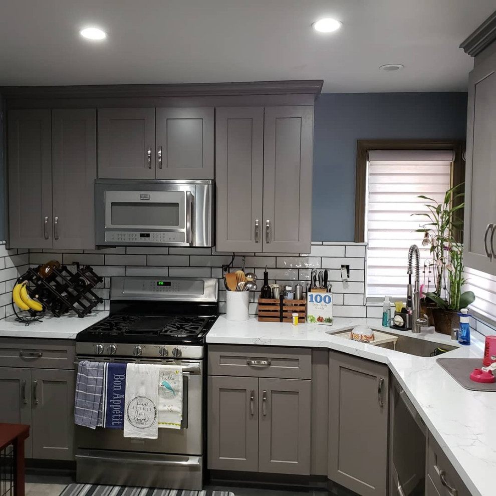 Inredning av ett litet vit vitt kök, med en undermonterad diskho, skåp i shakerstil, grå skåp, bänkskiva i kvarts, vitt stänkskydd, stänkskydd i tunnelbanekakel, rostfria vitvaror, klinkergolv i porslin och grått golv