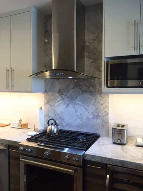 Small contemporary u-shaped kitchen in New York with a submerged sink, flat-panel cabinets, grey cabinets, quartz worktops, white splashback, stone tiled splashback and stainless steel appliances.