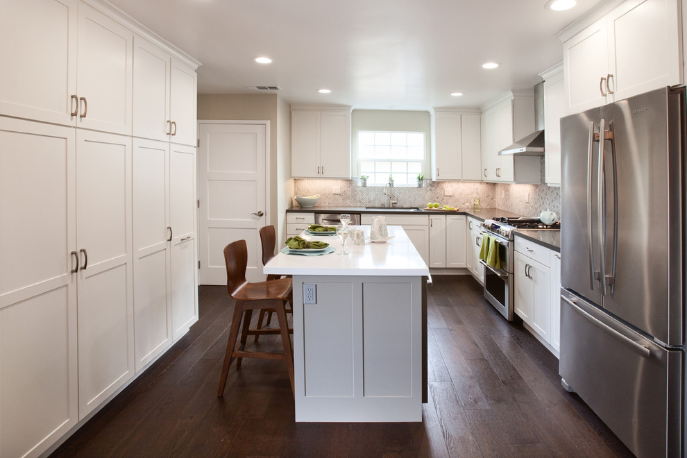 Example of a mid-sized transitional u-shaped medium tone wood floor eat-in kitchen design in Orange County with a double-bowl sink, shaker cabinets, white cabinets, quartz countertops, gray backsplash, stone tile backsplash, stainless steel appliances and an island