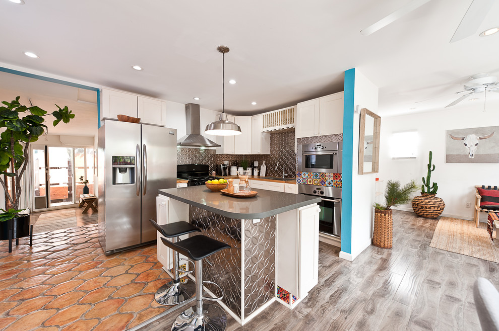 Example of a small trendy l-shaped enclosed kitchen design in Los Angeles with a double-bowl sink, flat-panel cabinets, white cabinets, metallic backsplash, metal backsplash and an island