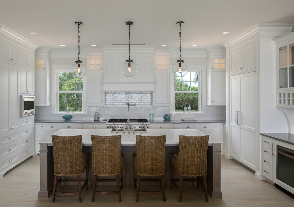 Kitchen - coastal light wood floor and beige floor kitchen idea in Tampa with recessed-panel cabinets, white cabinets, paneled appliances and an island