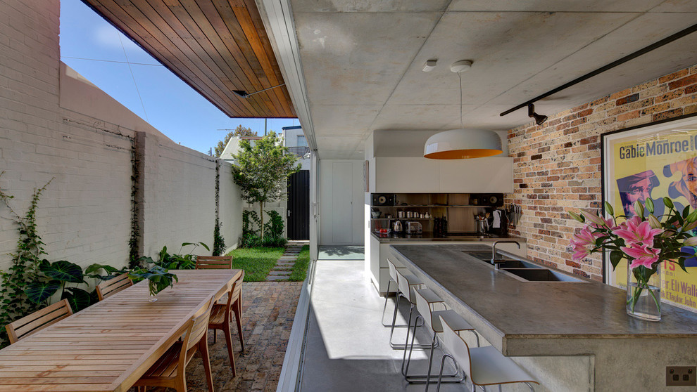 Inspiration för ett mellanstort funkis kök och matrum, med en nedsänkt diskho, bänkskiva i betong, stänkskydd i metallkakel, rostfria vitvaror, betonggolv och en köksö