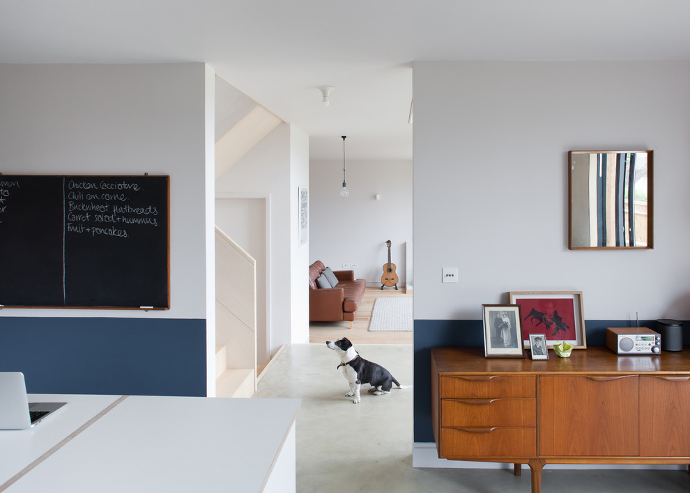 Cette image montre une cuisine ouverte linéaire nordique de taille moyenne avec un placard à porte plane, des portes de placard blanches, un plan de travail en bois, sol en béton ciré, îlot et un sol gris.