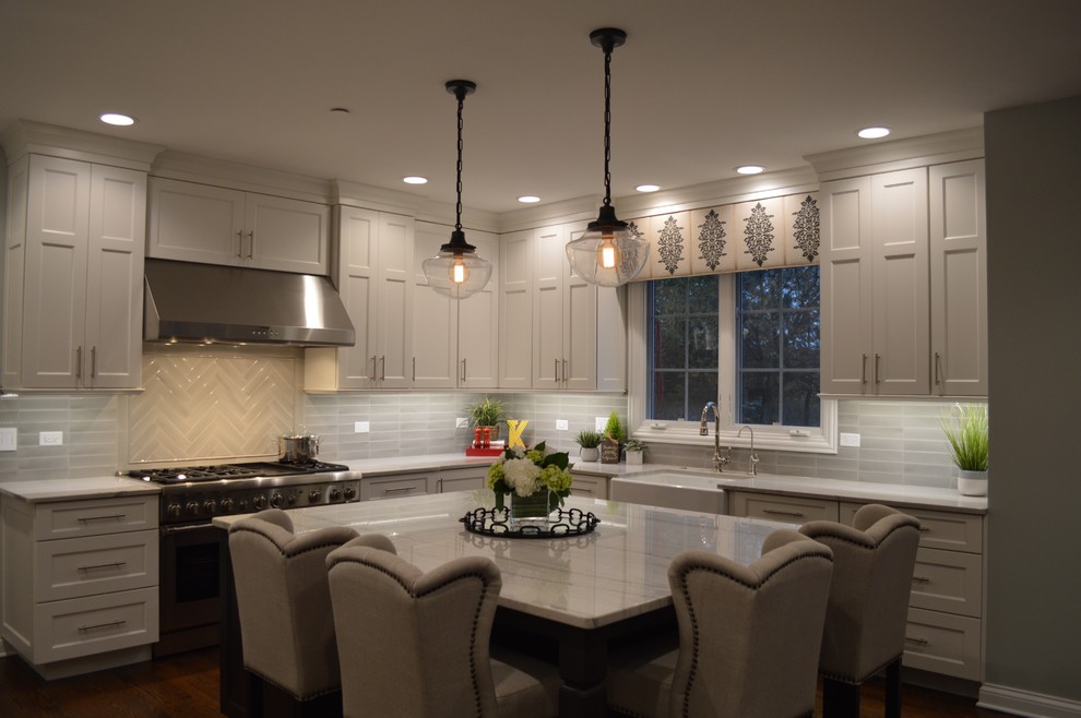 Medium sized traditional l-shaped kitchen in Chicago with a belfast sink, grey cabinets, engineered stone countertops, grey splashback, ceramic splashback, stainless steel appliances, medium hardwood flooring, an island and brown floors.