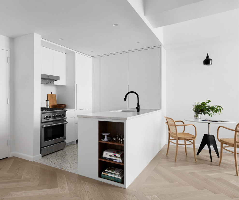 Minimalist u-shaped terrazzo floor and beige floor eat-in kitchen photo in New York with an undermount sink, flat-panel cabinets, white cabinets, quartz countertops, white backsplash, stainless steel appliances, a peninsula and white countertops