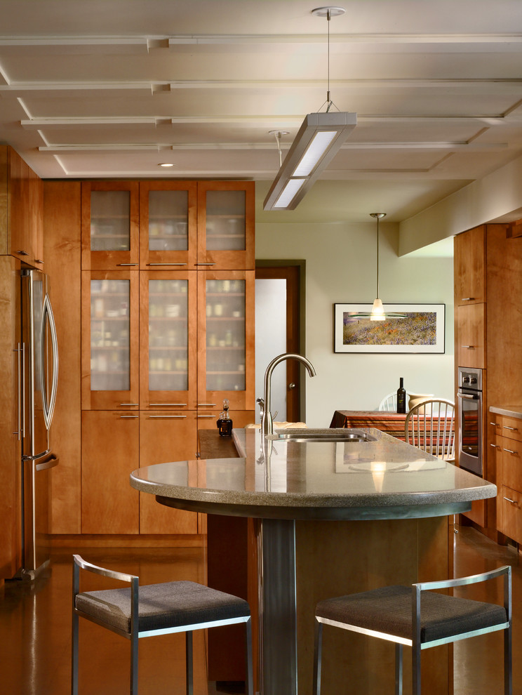 Mid-sized trendy galley vinyl floor and brown floor eat-in kitchen photo in Atlanta with a double-bowl sink, flat-panel cabinets, light wood cabinets, green backsplash, glass tile backsplash, stainless steel appliances, an island and solid surface countertops